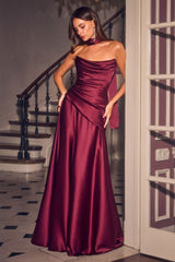 A woman models a floor-length, one-shoulder satin gown in a rich burgundy or deep wine color. The dress features a draped, ruched bodice and a matching high neck choker.