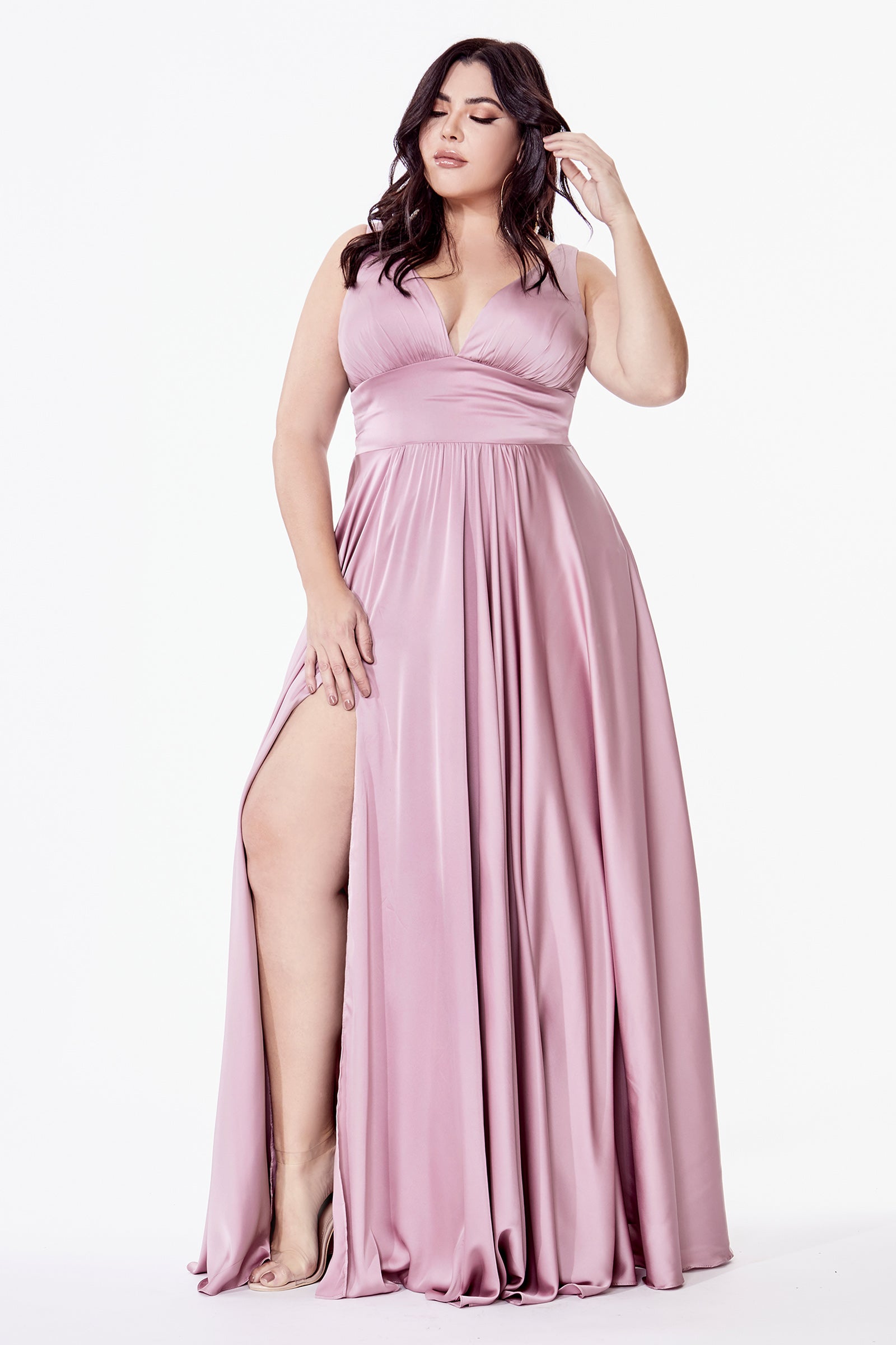 Woman wearing a pink evening gown with a high slit on a white background
