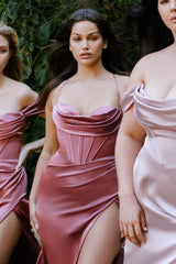 Three women in elegant dresses standing outdoors with greenery in the background
