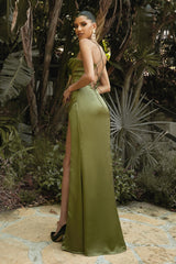 Woman in a green evening gown with a high slit standing in a garden setting.