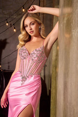 Woman in a pink evening gown with beaded details, standing against a warm-toned background.