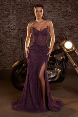 Woman in a purple eggplant strapless evening gown standing next to a motorcycle with a brick wall background