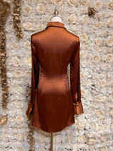 Brown satin long sleeve button up shirt dress displayed on a mannequin against a floral background.