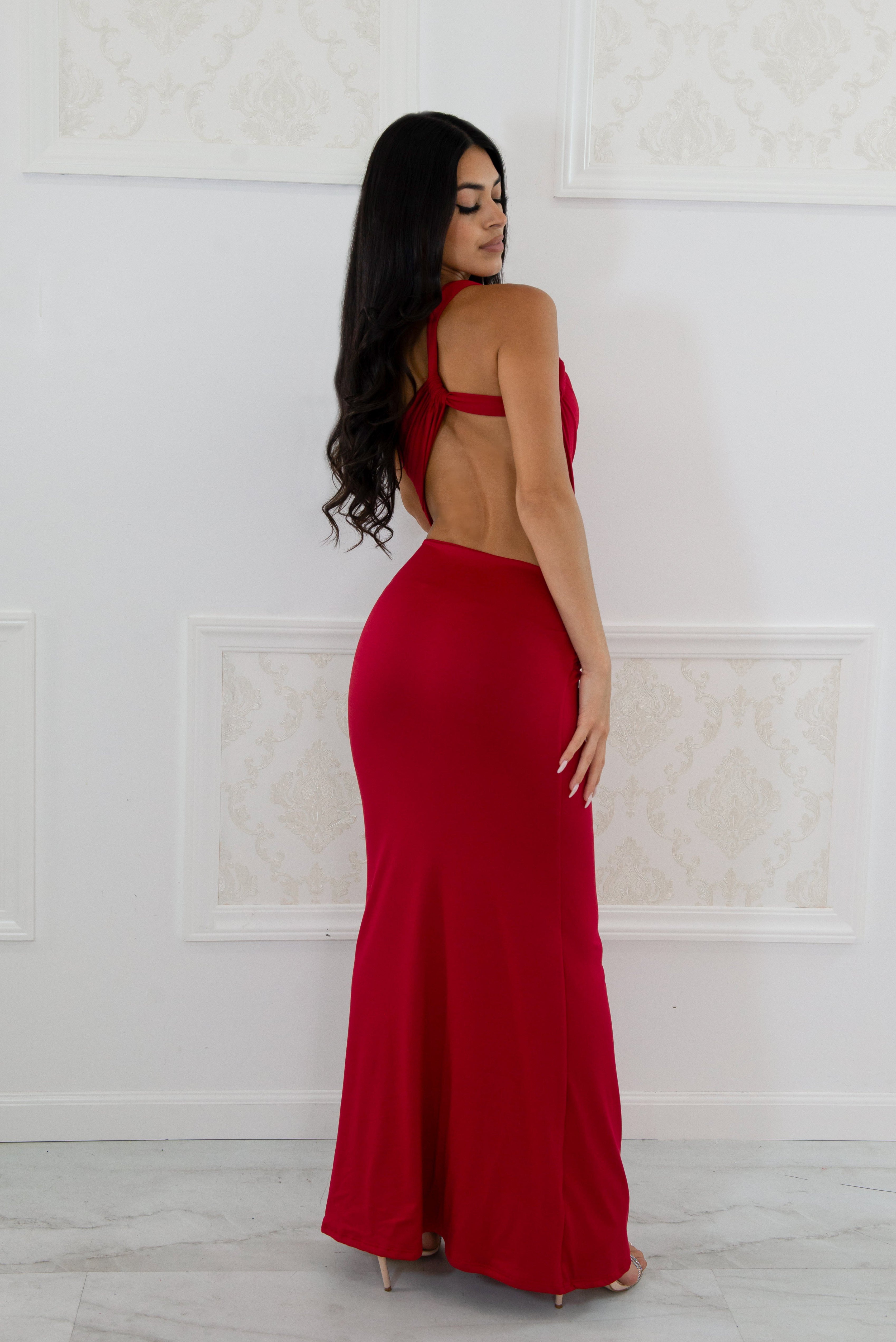 Model wearing a red one-shoulder maxi dress featuring a side waist cutout, front tie draping, and floor-length hem