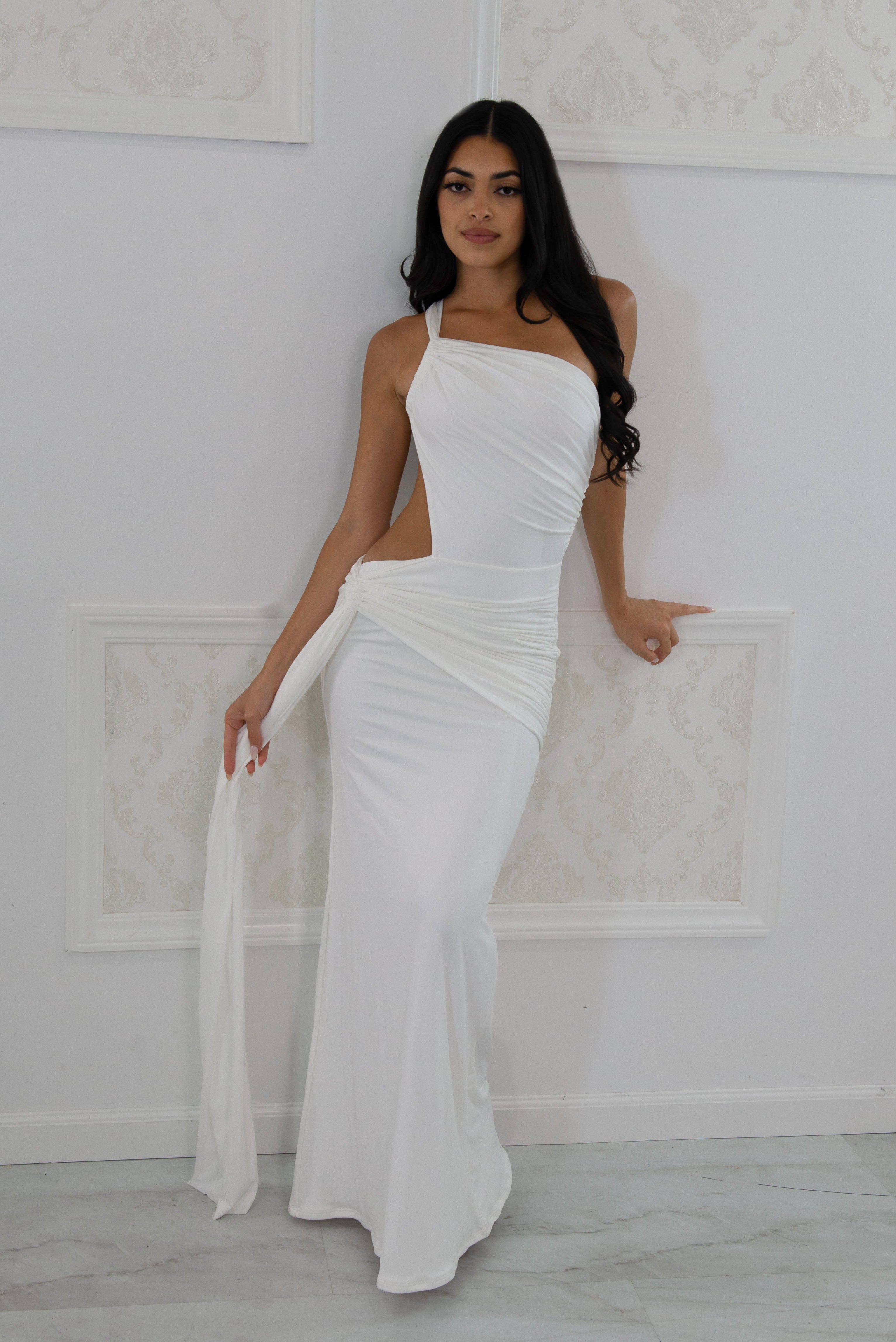 Model wearing a white one-shoulder maxi dress featuring a side waist cutout, front tie draping, and floor-length hem
