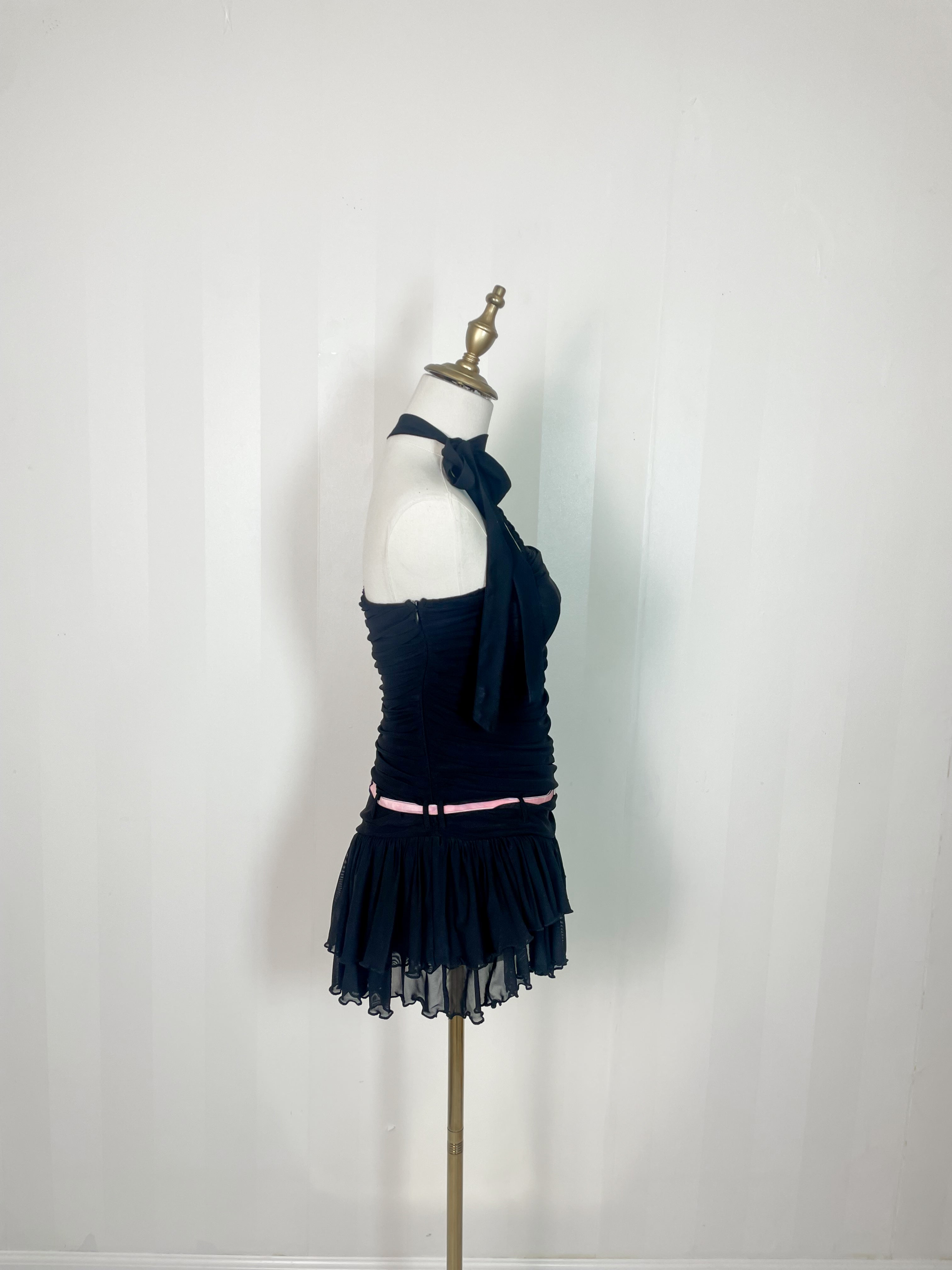 Black halter-neck ruched mini romper with ruffled hem and pink belt, displayed on mannequin