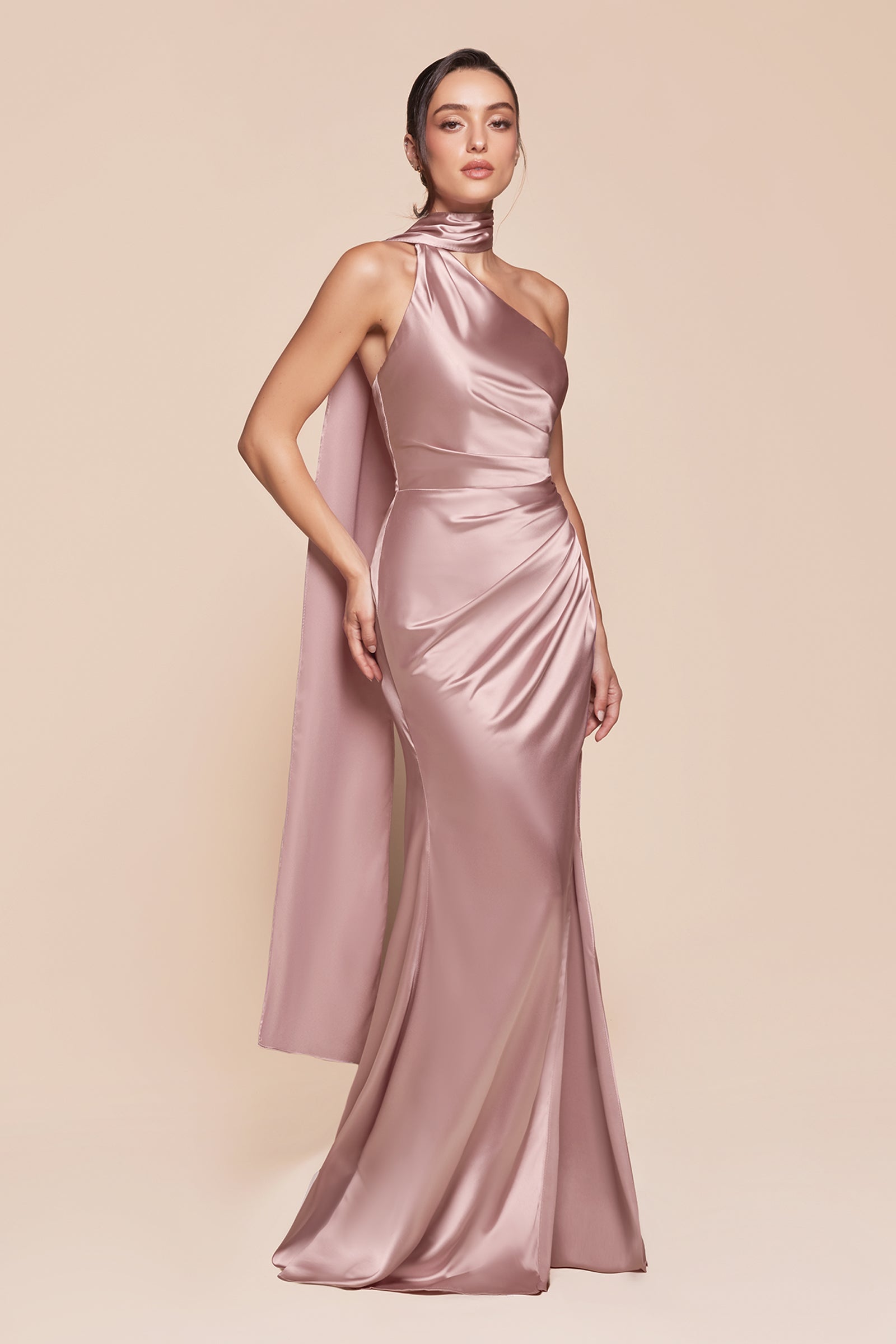 This fitted gown showcases a chic one-shoulder wrap halter neckline, with a gathered waistline and elegant leg slit for added allure