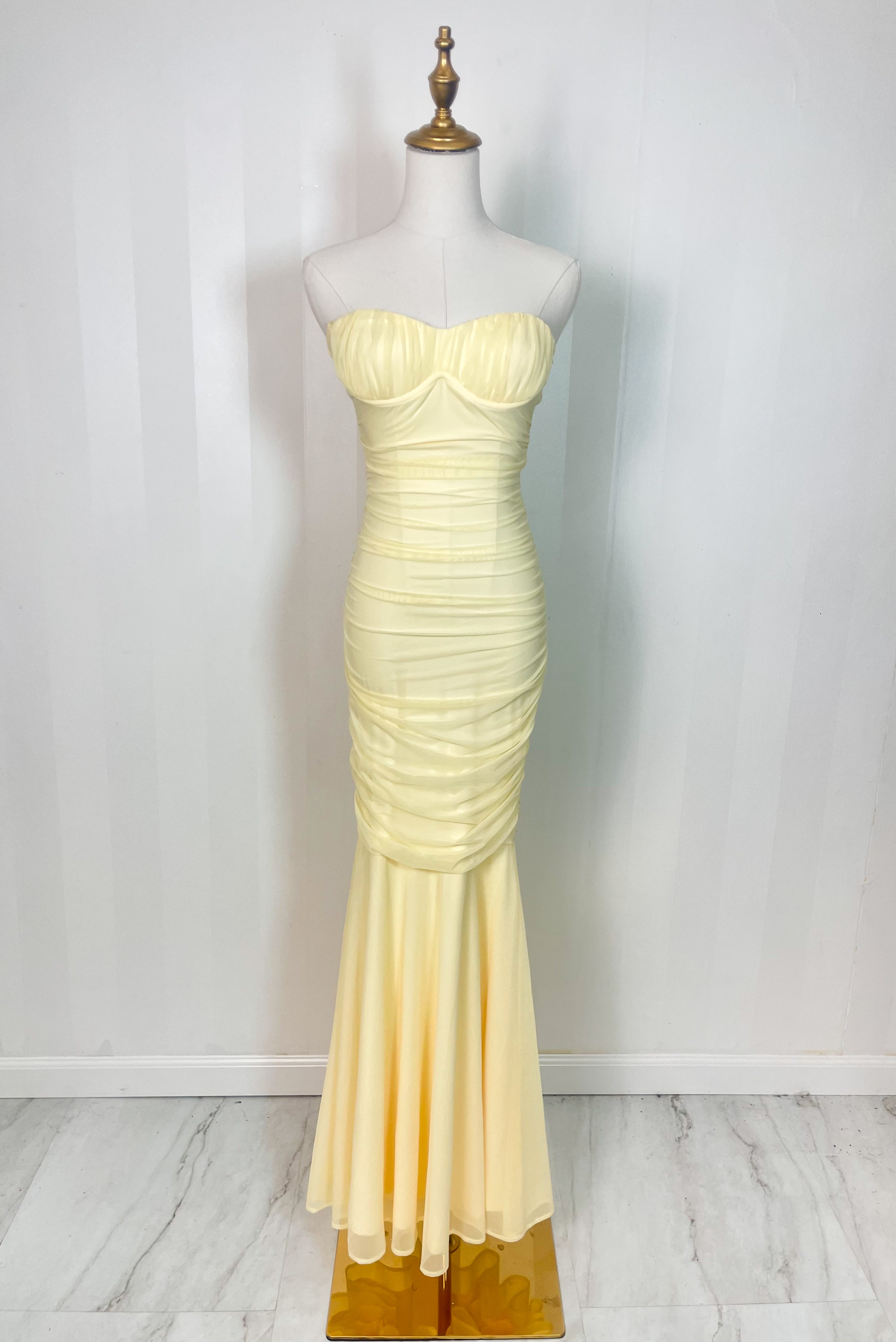 Yellow strapless ruched maxi dress with flared hem displayed on mannequin