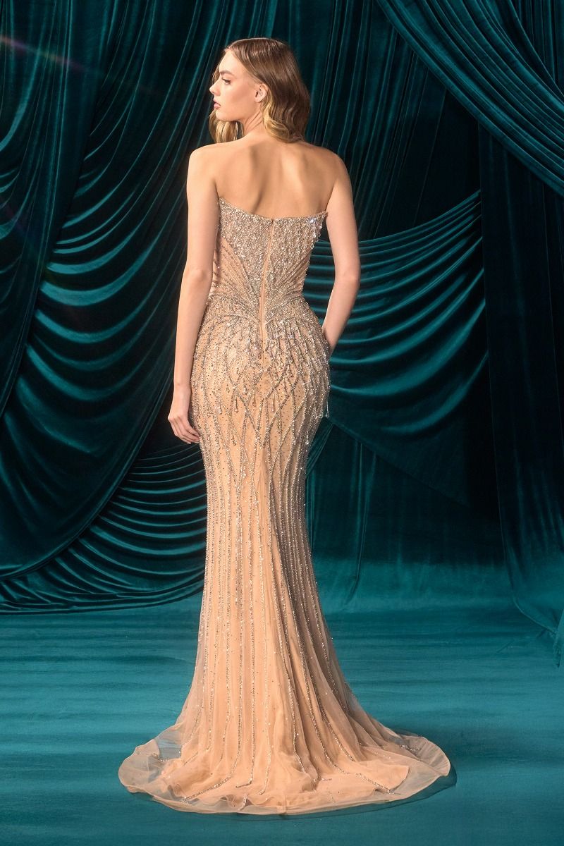 Woman in a beaded evening gown standing against a teal curtain backdrop