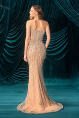 Woman in a beaded evening gown standing against a teal curtain backdrop