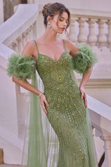 A woman models a sage green evening gown with intricate gold beadwork, sheer tulle flower sleeves, and a matching sheer train, posed on an outdoor stone staircase.