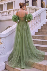 A woman stands on outdoor stone stairs wearing a formal sage green gown, photographed from the back. The dress has sheer tulle layers, beaded embellishments, a deep V back, and oversized ruffled flower sleeves.