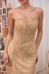 A strapless champagne gold beaded gown with a sweetheart neckline, featuring intricate sequin and bead detailing that radiates from the center, worn by a model in an indoor setting.