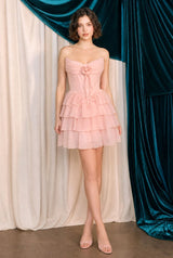 Woman wearing a pink strapless dress standing in front of blue and white draped curtains.