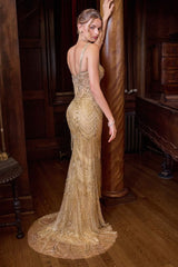 A woman wearing a floor-length champagne gold beaded evening gown with a halter back and dramatic train, posed in a dark wood-paneled room.