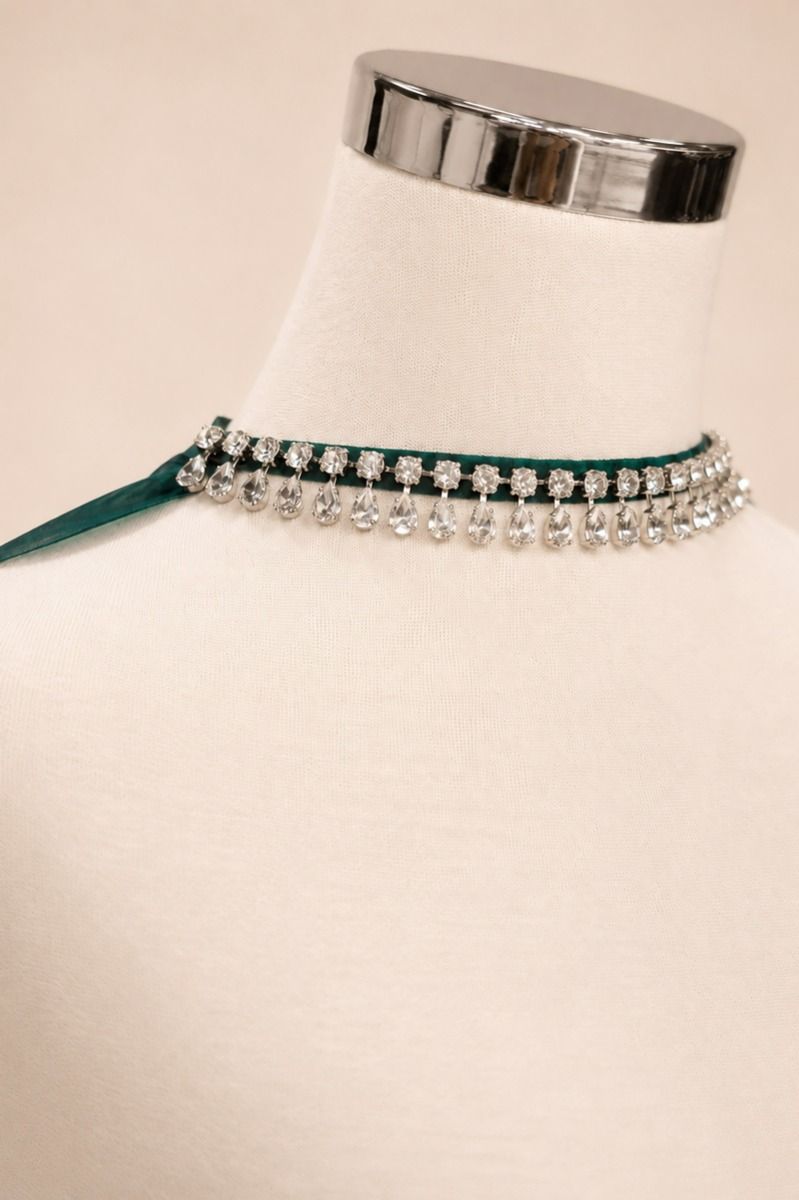A double-row rhinestone choker necklace with a dark green ribbon base, displayed on a cream-colored mannequin bust.