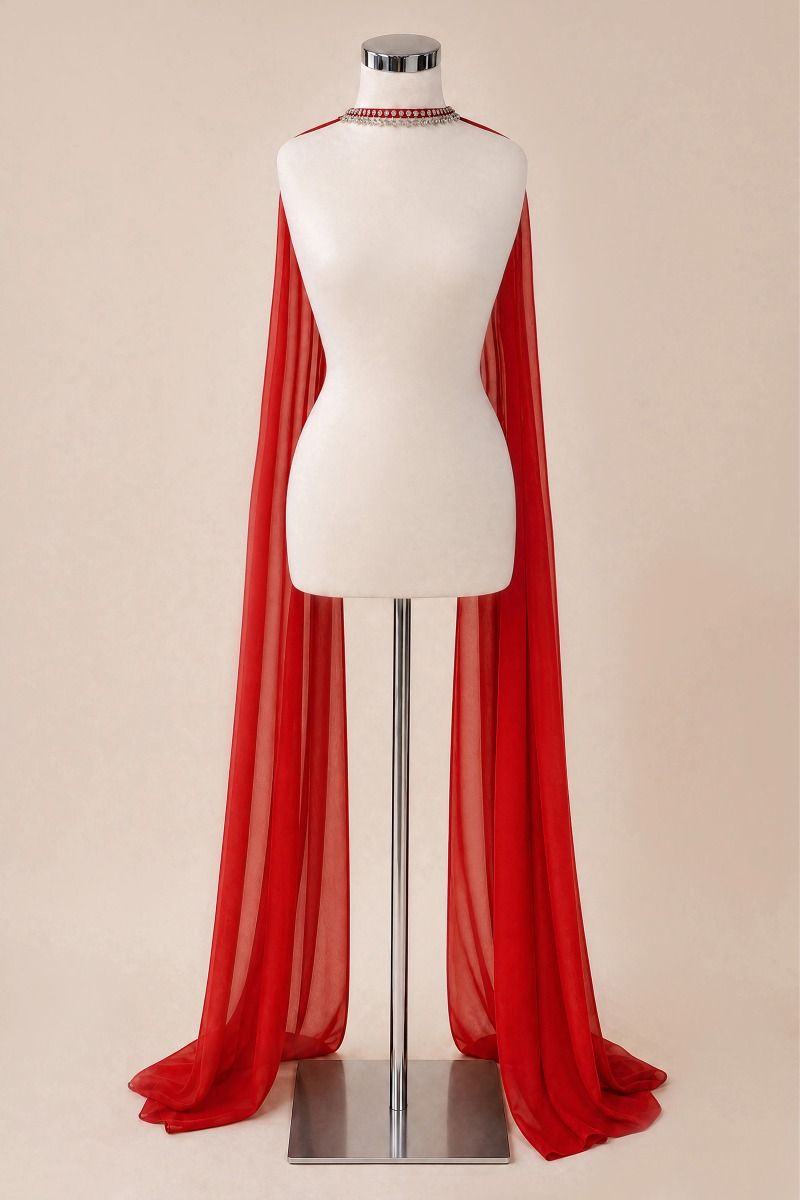 A bright red sheer draped cape or shawl displayed on a white mannequin torso with a silver stand against a plain beige studio background.