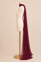 A long, sheer burgundy scarf draped over a cream-colored dress form on a gold stand, set against a solid beige background.