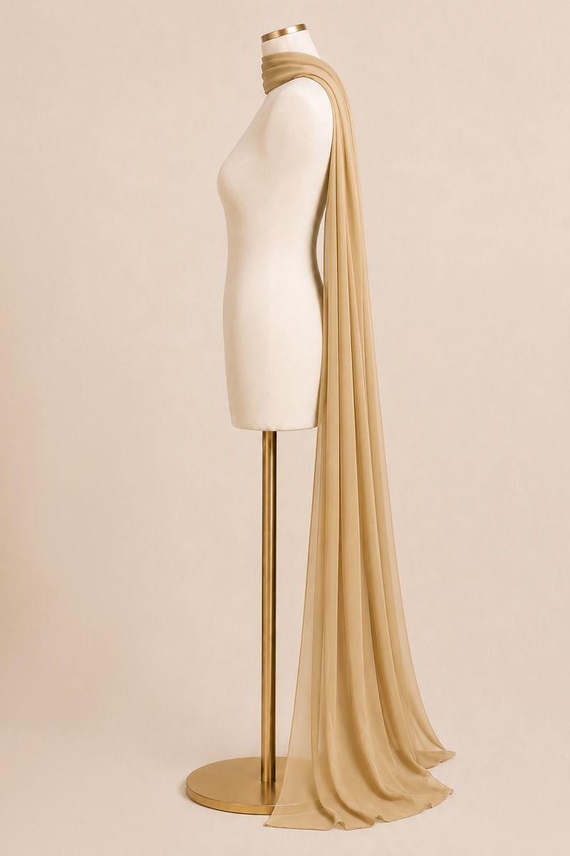 A draped beige scarf or shawl displayed on a cream mannequin torso with a gold stand against a plain beige studio background.