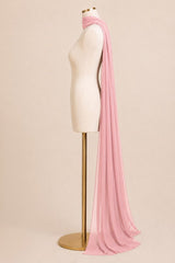 A long, lightweight pink scarf draped over a cream-colored dress form mannequin on a gold stand, set against a solid light beige background.