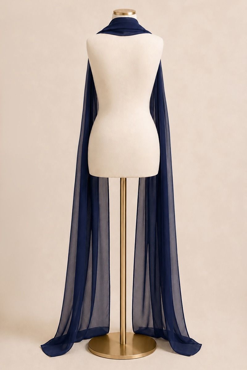 A long sheer navy blue scarf draped over a cream dress form mannequin on a gold stand, set against a solid beige background.