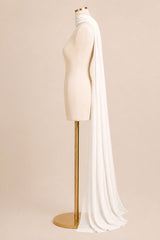 A long flowing white bridal veil draped over a cream mannequin torso on a gold stand, photographed against a warm beige studio background.