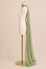 A sage green sheer scarf draped over a cream-colored mannequin torso on a gold stand, set against a solid beige background.