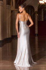 Model wearing a fitted evening gown with thin straps, plunging neckline, lace-up open back, and high side slit, detailed with shimmering embellishments and floor-length train