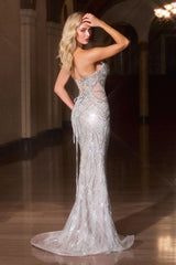 Woman in a silver evening gown with intricate detailing in an elegant indoor setting.
