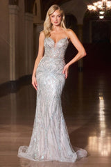 Woman in a sparkling evening gown standing in an elegant indoor setting.