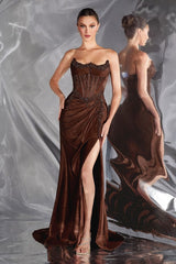 Woman wearing a brown evening gown with a high slit on a gray background