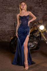 Woman in a blue evening gown standing next to a motorcycle with a brick wall background