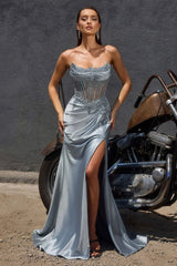 Woman in a silver evening gown standing next to a motorcycle against a dark background