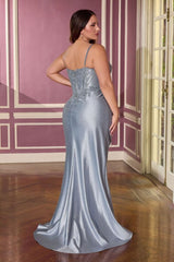 Woman in a silver evening gown standing in a room with pink walls and wooden floor.