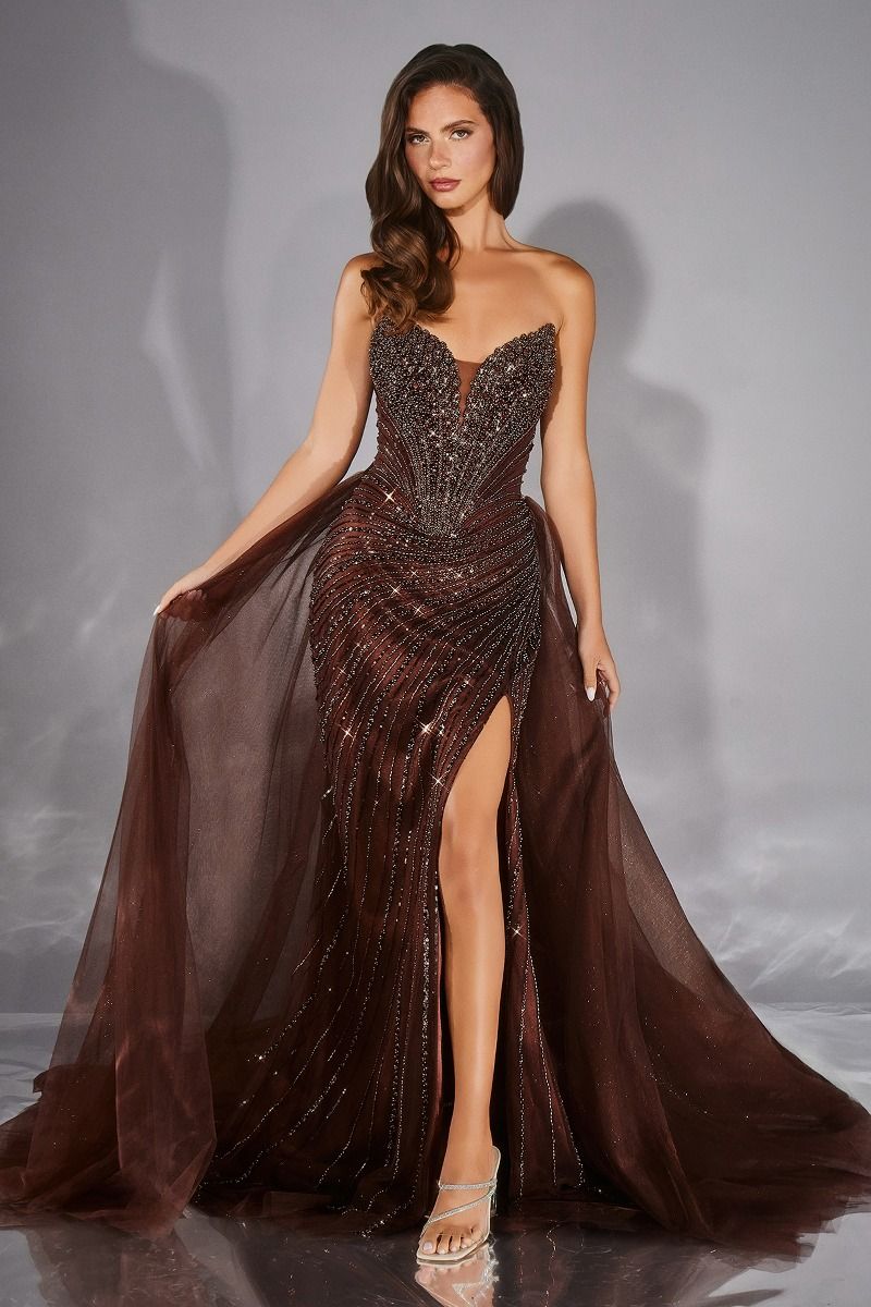 Woman wearing a brown beaded evening gown with a slit on a gray background