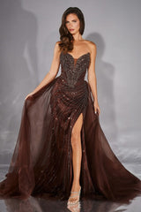 Woman wearing a brown beaded evening gown with a slit on a gray background