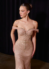 Woman wearing a sparkling off-shoulder gown against a dark background