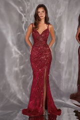 Woman wearing a red sequin evening gown with a high slit on a reflective surface.