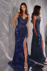 Woman wearing a blue sequin evening gown with a high slit on a reflective surface.