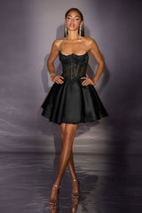 Woman wearing a black dress with a textured bodice and flowing skirt against a gray background