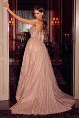 A woman wearing a strapless dusty pink tulle ball gown with a fitted embellished bodice and a full flowing skirt, posed in a dimly lit, elegant room with candles.