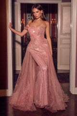A woman models a strapless, floor-length pink tulle gown with sequined embellishments in an elegant indoor hallway.