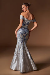 Woman wearing a silver and blue floral off-shoulder gown against a brown background
