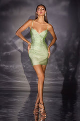 Model wearing a green dress on a dark, textured background
