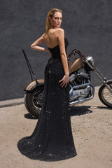 Model wearing a fitted gown featuring a draped bodice with sheer overlay, high side slit, and matching scarf accessory