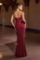 Woman in a red sequin evening gown standing in an elegant hallway.