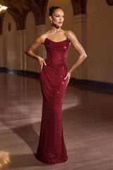 Woman in a red sequin gown standing in an elegant interior setting.