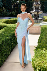 Woman in a light blue evening gown standing in a garden with a fountain.