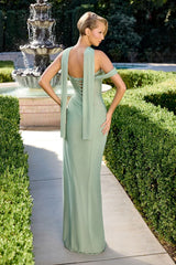 Woman in a light green evening gown standing in a garden with a fountain.