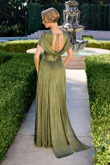 Woman in a green evening gown standing in a garden with a fountain.